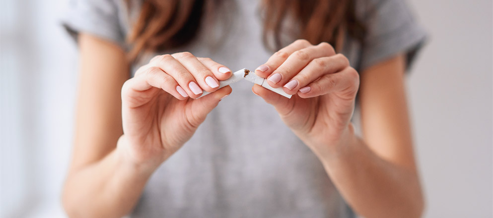 Een vrouw houdt een sigaret in haar hand en breekt deze doormidden.